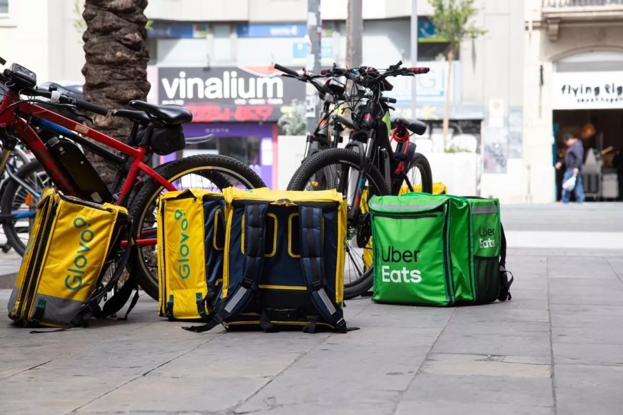 Plecaki dostawców żywności, Uber Eats i Glovo, na chodniku w Barcelonie (Shutterstock)