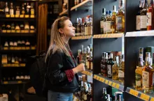 Kobieta wybiera alkohole mocne w sklepie (fot. andreonegin/Shutterstock)