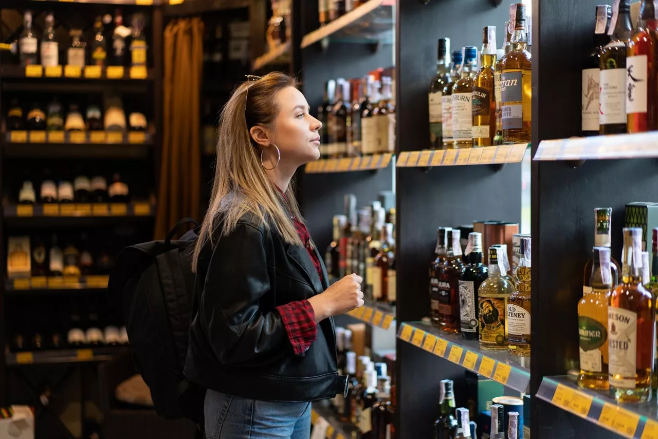 Kobieta wybiera alkohole mocne w sklepie (fot. andreonegin/Shutterstock)