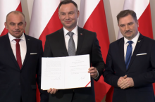 &lt;p&gt;Prezydent Andrzej Duda prezentujący podpis pod ustawą o ograniczeniu handlu w niedziele, 2018 r. Obok niego Alfred Bujara i Piotr Duda z Solidarności (fot. YouTube)&lt;/p&gt;