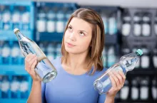 Looking up woman holding two glass bottle with water