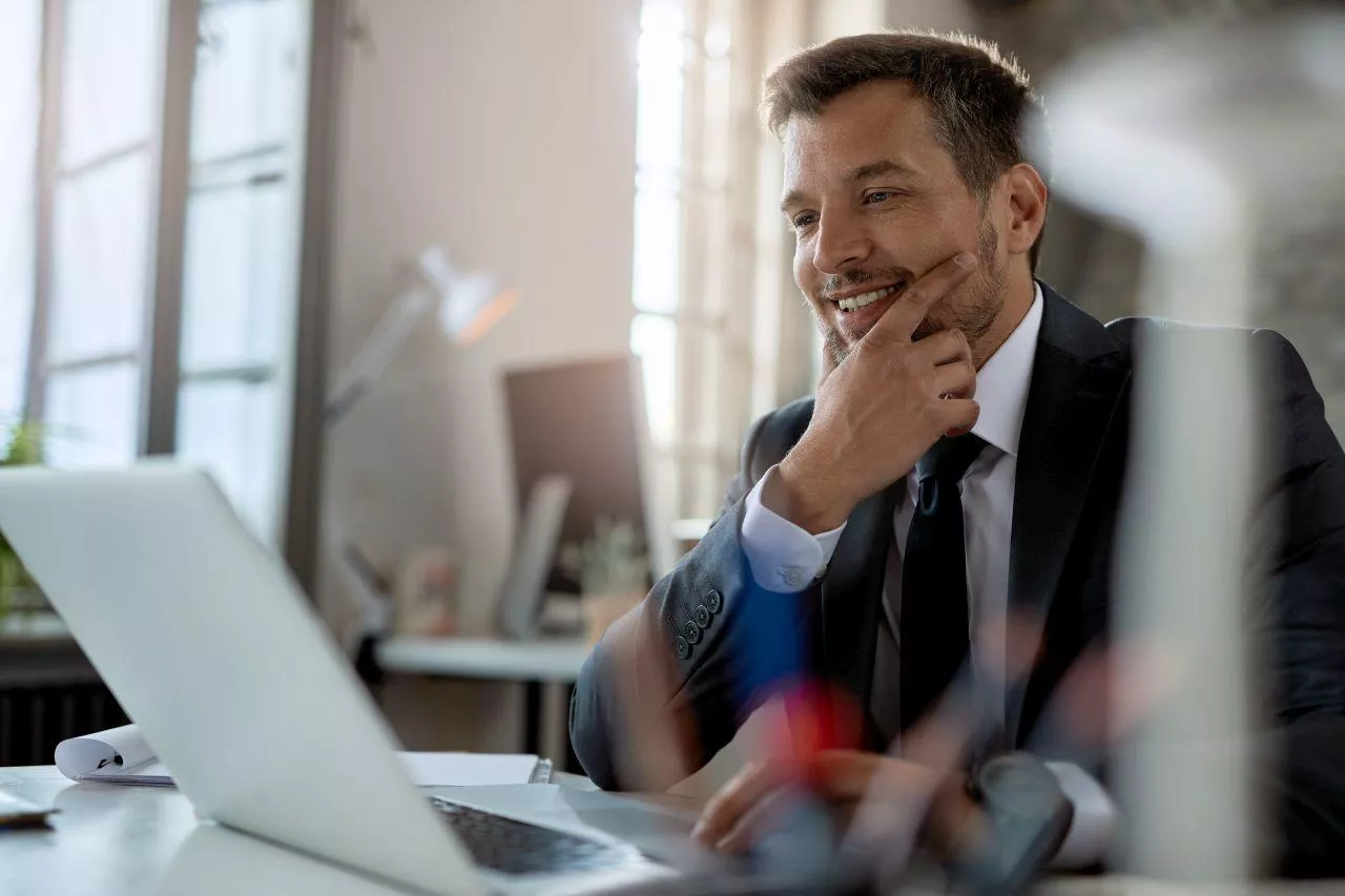 Smiling mid adult businessman using computer while working at office desk.