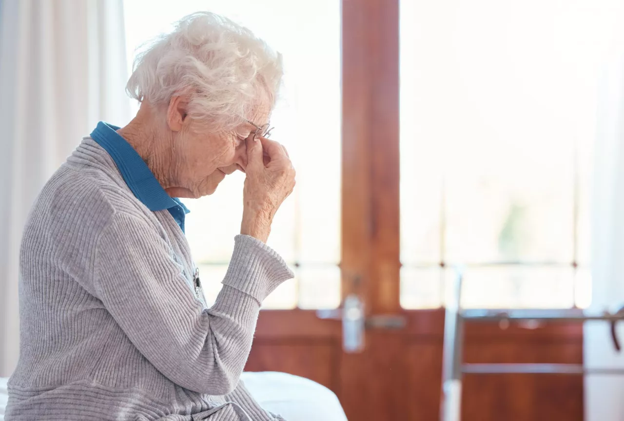 Senior woman, headache and stress with anxiety in retirement house, lonely and sad with mental heal.