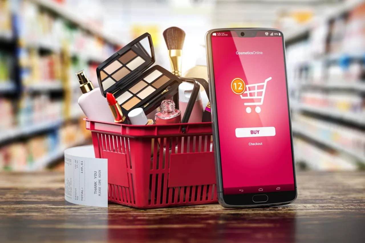 Cosmetics and beauty products buying online concept. Shopping basket with makeup products and mobile phone on shelf of cosmaetics shop. 3d illustration