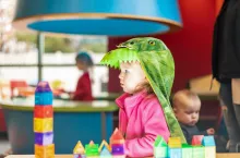 Toddler girl dressed in a dinosaur costume playing with toys - creative play