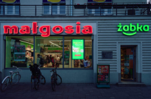 Neon ”Małgosia”, który przez lata zdobił sklep w przyziemiu kamienicy przy ul. Toeplitza 2, wrócił na swoje pierwotne miejsce dzięki zaangażowaniu zespołu Żabki, franczyzobiorcy Krzysztofa Liegmanna