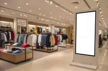 Modern vertical lightbox display inside a stylish clothing store, ideal for showcasing indoor advertisements or branding designs in retail environments.